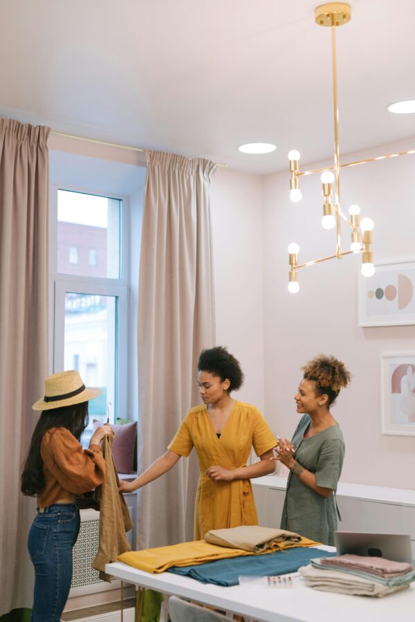 Three women assess various fabrics in a room, reflecting their focus on interior design in Delhi and curtain design.