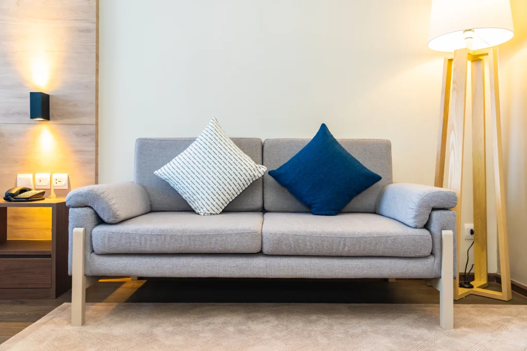 A blue couch with a quilted cover, exemplifying contemporary interior design in Delhi, paired with chic cushions for added comfort.