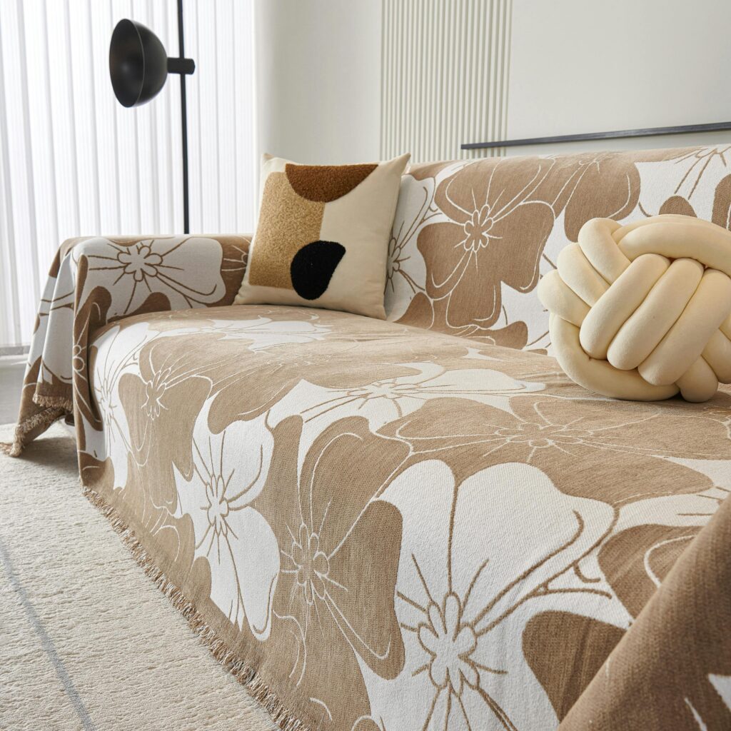 A comfortable couch with a blanket and a ball, emphasizing chic sofa cover and cushions, suitable for interior design in Delhi.